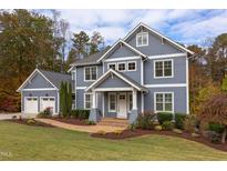 Inviting two-story home features a well-kept lawn, colorful landscaping, brick walkway, and a spacious two-car garage at 415 Westbury Dr, Chapel Hill, NC 27516
