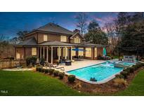 Stunning brick home with a backyard oasis including a large pool, patio, and outdoor seating area at 5301 Mandrake Ct, Raleigh, NC 27613
