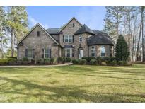 Beautiful two-story brick home with a well-manicured lawn and mature trees at 7220 Hasentree Way, Wake Forest, NC 27587