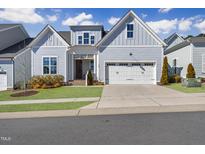 Charming home showcasing light blue siding, a two-car garage, and a well-manicured lawn at 729 Daniel Ridge Rd, Wendell, NC 27591
