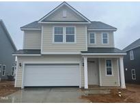 Two-story home featuring attached two-car garage, neutral siding, white trim, and a classic, gabled roof design at 89 Willow Cameron Way, Angier, NC 27501