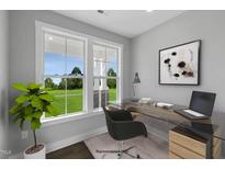 Bright office with a large window overlooking a beautiful green lawn, complemented by a modern glass desk and chair at 53 Merele Dr, Wendell, NC 27591