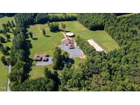 Stunning aerial view of the horse property with fenced pastures, barn, and residences surrounded by mature trees at 1018 Terrell Woods Ln, Chapel Hill, NC 27516