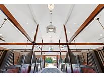 Stunning barn interior with brick flooring, wood beams, and stalls with metal gates and wood paneling at 1018 Terrell Woods Ln, Chapel Hill, NC 27516