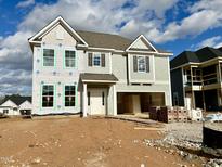 New construction two-story home showcasing a neutral color, two-car garage and unfinished yard space at 15 Nimble Way # 175, Clayton, NC 27520