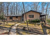 Charming single-story home featuring wood siding, dark trim, and landscaped front yard surrounded by mature trees at 2107 Markham Dr, Chapel Hill, NC 27514