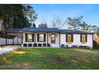 Charming brick home features manicured lawn, black trim, covered carport and inviting front porch at 226 Pinecroft Dr, Raleigh, NC 27609
