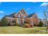 Beautiful brick home featuring a manicured lawn and elegant architectural details under a clear blue sky at 4270 Aviemore Run, Burlington, NC 27215