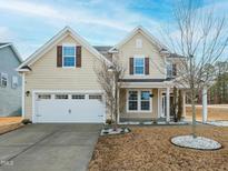 Charming home featuring a two-car garage, a well-manicured lawn, and a welcoming front porch at 800 Tree Green Ln, Wake Forest, NC 27587