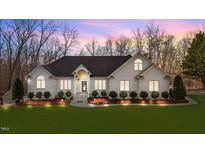 Beautifully landscaped white brick home featuring a manicured lawn, stylish entrance and accent lighting at 1002 Pleasant Dr, Mebane, NC 27302