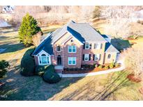 Aerial shot of a brick two-story home, showcasing landscaping and a nearby pond at 10620 Staghound Trl, Zebulon, NC 27597