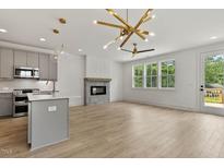 Open-concept living room features a modern fireplace, stainless appliances, and large windows at 136 E End Ave # 4, Durham, NC 27703