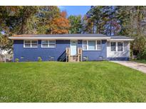 Charming one-story home featuring a blue painted brick and a well-manicured front lawn at 3305 Friar Tuck Rd, Raleigh, NC 27610