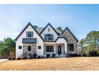 Charming two-story home featuring a landscaped yard and a mix of white siding and stone accents at 8621 Bishop Pine Ln, Wake Forest, NC 27587