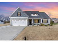 Charming home featuring a two-car garage and inviting front porch at 241. The lawn needs some TLC at 241 N Nolan Park Dr, Selma, NC 27576