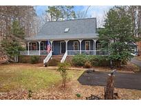 Charming blue home featuring a welcoming front porch with white railings and brick stairs at 2616 Countrywood Rd, Raleigh, NC 27615
