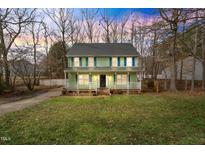 Two-story home featuring a front porch, lush lawn, and a welcoming facade with blue shutters at 5511 Hadrian Dr, Durham, NC 27703