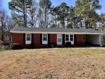 Charming one-story brick home with an attached carport and well-maintained front yard and established trees at 613 Sexton Ave, Zebulon, NC 27597