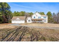 Inviting two-story home featuring a spacious front porch and a detached three-car garage on expansive lot at 1175 Faulkner Town Rd, Henderson, NC 27537