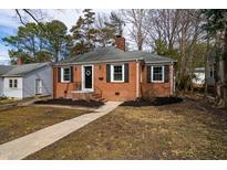 Charming brick ranch-style home with a welcoming front yard, black shutters, and a classic chimney at 2204 Guess Rd, Durham, NC 27705