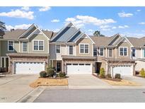 Charming townhomes with attached garages and lovely stone and siding exteriors under a blue sky at 468 Talons Rest Way, Cary, NC 27513