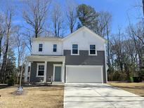Charming two-story home with gray and white siding, a two-car garage, and a well-manicured front lawn at 704 Mirror Pond Dr, Zebulon, NC 27597