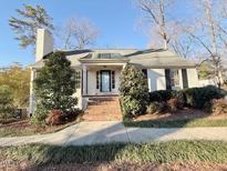 Charming home featuring a brick walkway leading to the front door and lush landscaping at 708 Macon Pl, Raleigh, NC 27609