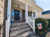 Inviting stone front porch with classic white railing and charming welcome decor at 108 Leafy Holly Dr, Holly Springs, NC 27540