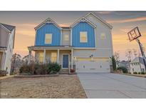 Charming two-story home featuring a well-manicured lawn, a two car garage and inviting blue accents at 1600 Tinos Overlook Way, Apex, NC 27502
