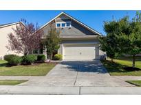 Charming home with a two-car garage and a well-manicured front yard with mature trees on a sunny day at 1707 Capstone Dr, Durham, NC 27713