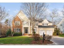 Charming home featuring brick and tan siding, a well-manicured lawn, and a two-car garage at 203 Preston Oaks Ln, Cary, NC 27513