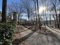 Charming brick home featuring a well-maintained yard with mature trees on a sunny day at 8701 Oneal Rd, Raleigh, NC 27613