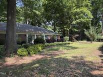 Traditional brick home featuring a well-manicured front lawn and mature landscaping with trees and shrubs at 8701 Oneal Rd, Raleigh, NC 27613