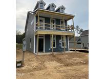 New construction home featuring Hardie siding, three dormers and a covered porch on a lot prepped for landscaping at 304 White Oak Garden Way # 214, Garner, NC 27529