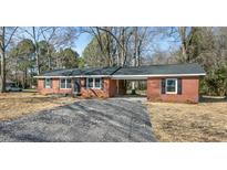 Charming red brick home featuring a gravel driveway, covered carport, and nicely trimmed landscaping at 3639 Nc Highway 39, Selma, NC 27576