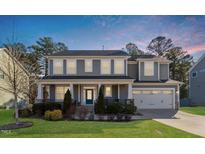 Charming two-story home features a covered front porch, manicured lawn, and attached two-car garage at 401 River Falls Dr, Apex, NC 27539