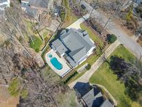 An aerial view of an estate home with a swimming pool and beautifully landscaped lawns and hardscapes at 7621 Wingfoot Dr, Raleigh, NC 27615