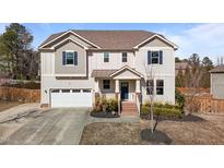 Charming two-story home featuring a two-car garage and a welcoming front porch with brick steps and landscaped garden at 104 Highland Mist Cir, Apex, NC 27539