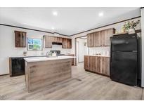 Well-lit kitchen featuring wood grain cabinets, modern appliances, and a convenient island with a white countertop at 112 Mckoy Town Rd, Cameron, NC 28326
