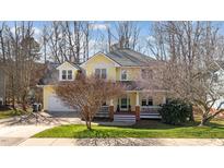 Charming yellow two-story home with a welcoming front porch and well-manicured lawn at 113 Magnolia Breeze Ct, Apex, NC 27502