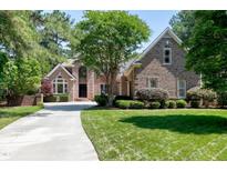 Traditional brick home featuring manicured lawn and long driveway, surrounded by lush, mature trees at 12085 Morehead, Chapel Hill, NC 27517