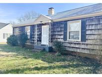 Charming single-story home with a front entrance framed by white posts and a well-maintained front lawn at 210 E Elk St, Siler City, NC 27344