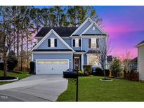 Charming two-story home with manicured lawn, driveway, and beautiful blue facade at 2409 Heathcote Ln, Apex, NC 27502