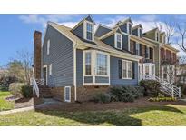 Charming townhome with blue siding, brick accents, manicured landscaping, and dormer windows at 2820 Bedfordshire Ct, Raleigh, NC 27604