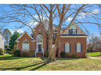 Charming two-story brick home featuring a well-manicured lawn and beautiful mature trees in the front yard at 409 Cricketfield Ln, Cary, NC 27518