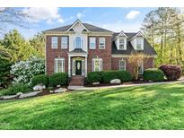 Stately two-story brick home featuring a manicured lawn and mature landscaping at 1154 Smith Creek Way, Wake Forest, NC 27587