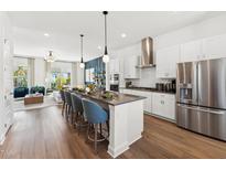 Open-concept kitchen featuring a large island with seating, stainless steel appliances, and wood flooring at 2800 Kempthone Rd # 65, Cary, NC 27519