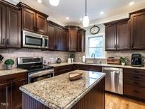 Well-equipped kitchen with stainless appliances, granite counters, and dark wood cabinets at 3117 Campbell Rd, Raleigh, NC 27606