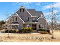 Traditional brick home featuring dormers, black shutters, and a well-manicured yard on a bright day at 4009 Banks Stone Dr, Raleigh, NC 27603