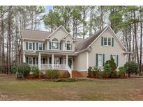 Charming two-story home boasts a welcoming front porch, complemented by lush landscaping and classic green shutters at 5309 Shoreline Ct Ct, Holly Springs, NC 27540